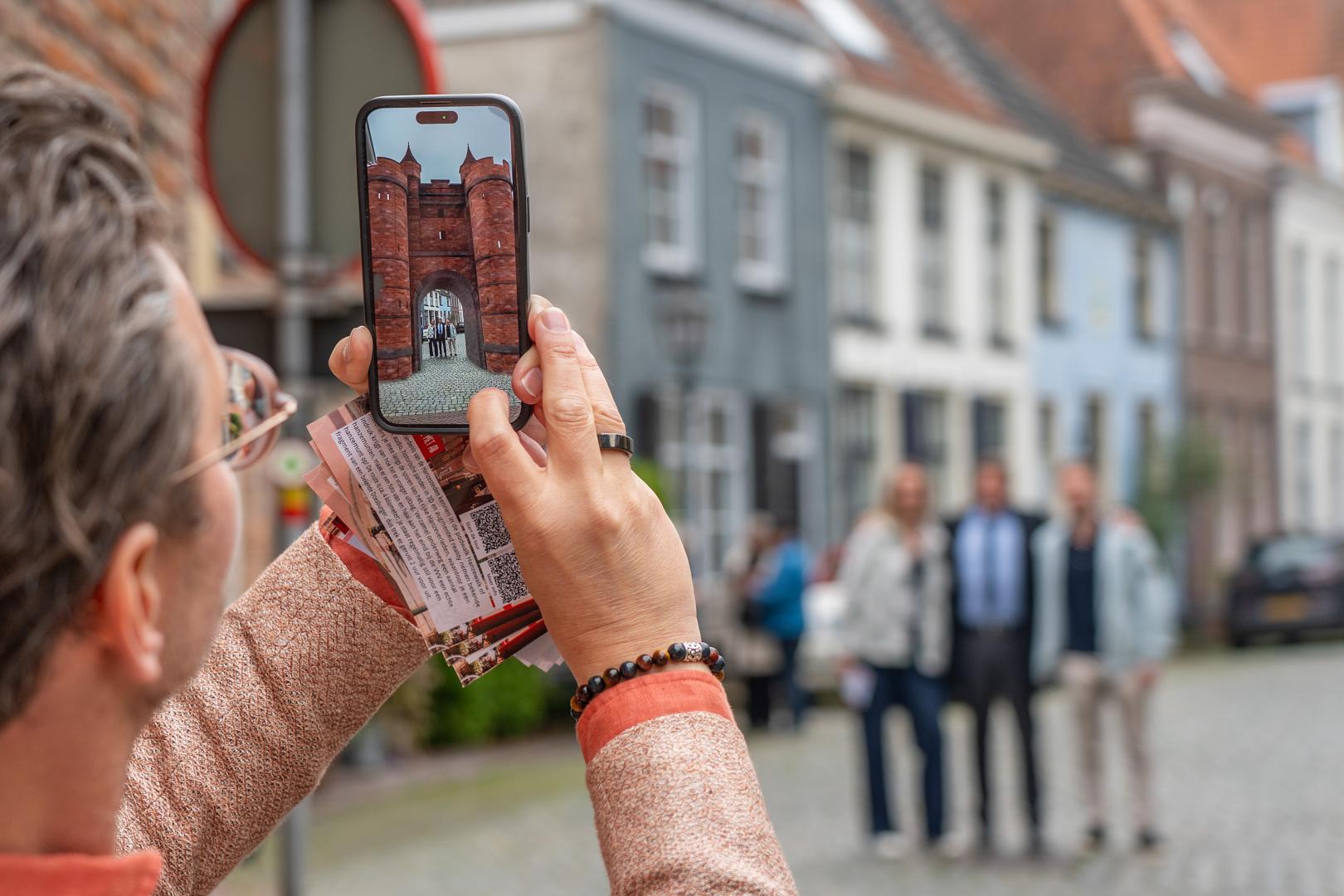 Hanzestad Doesburg met man met telefoon die met AR oude stadspoort op zijn plek zet en mensen erin fotografeert