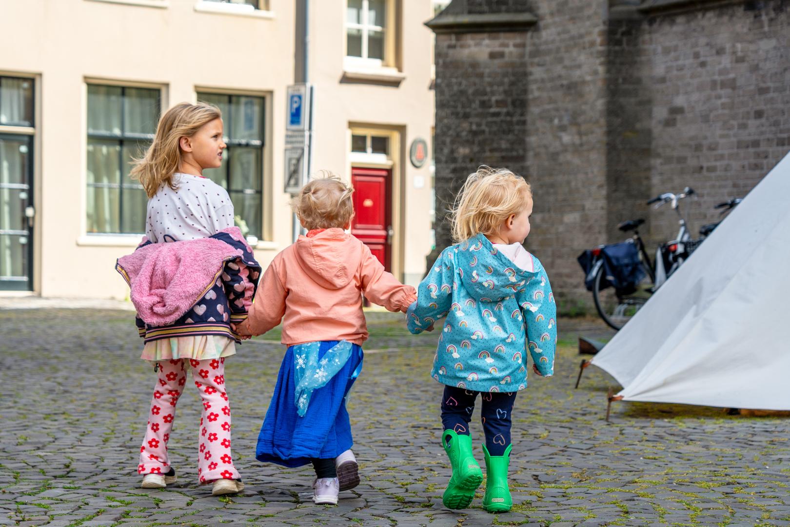 Drie kleine kinderen lopen hand in hand in Doesburg